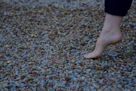 Téléchargez les photos : Image du pied féminin nu touchant à peine de petites pierres acérées vue de côté - en image libre de droit