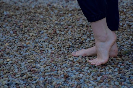 Photo for Image of bare female feet standing on small sharp stones making a step side view - Royalty Free Image
