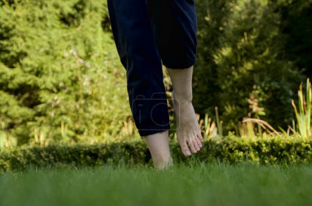 Téléchargez les photos : Image de pieds femelles nus debout sur de l'herbe fraîche humide faisant un pas vers l'avant vue de face - en image libre de droit