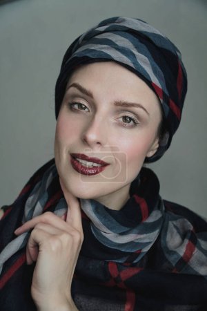 Portrait of a woman wearing dark bold lipgloss contrasting with pale skin and a shawl around her head