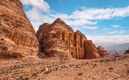 Foto de Ad Deir - Monasterio - ruinas talladas en la pared rocosa en Petra Jordania, terreno montañoso con fondo azul cielo - Imagen libre de derechos