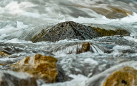 Téléchargez les photos : Rivière printanière rapide qui coule sur des roches formant des vagues d'eau vive, détail rapproché - fond naturel abstrait - en image libre de droit