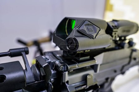 Aiming optics with green lens on heavy gun displayed at weapons fair - closeup detail