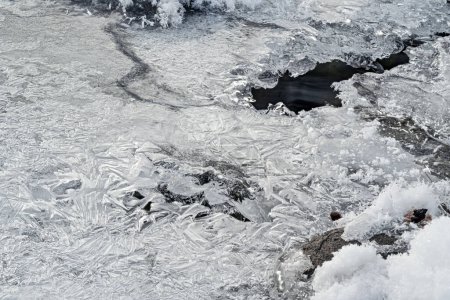 Téléchargez les photos : Rivière gelée en hiver recouverte de glace cristalline mince, photo à angle bas, trou avec de l'eau coulant sous - en image libre de droit