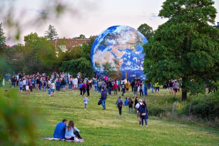 Téléchargez les photos : Brno, Tchéquie - 12 juillet 2020 : Des gens marchent devant un modèle gonflable de la Terre placé sur une prairie d'herbe verte près du parc planétarium - en image libre de droit