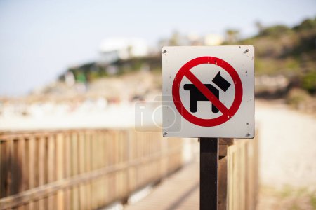 Téléchargez les photos : Rouge et noir pas de chien autorisé signe sur le chemin en bois menant à la plage - en image libre de droit