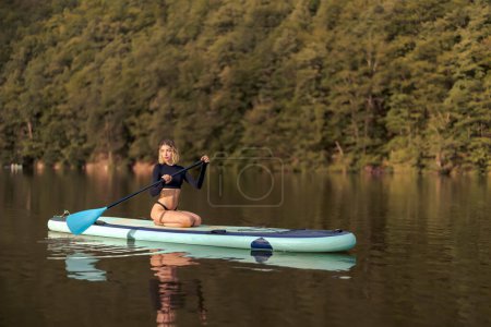 Téléchargez les photos : Belle femme sexy se détendre sur stand up paddle, Tarnita lac, Roumanie - en image libre de droit