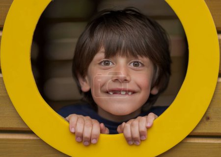 Téléchargez les photos : Charmant gamin regardant à travers une décoration de trou dans un parc d'attractions - en image libre de droit
