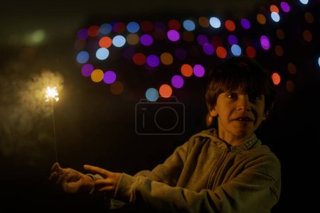 Foto de Lindo chico sosteniendo fuegos artificiales, mirando emocionado - Imagen libre de derechos