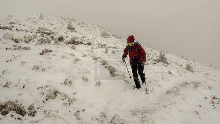 Téléchargez les photos : Femme sportive profitant d'une randonnée hivernale dans les montagnes enneigées, temps violent - en image libre de droit