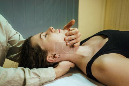 Foto de Una mujer en una sesión de tratamiento de TSC, manipulación osteopática y terapia craneosacra. Medicina no tradicional. Asistencia sanitaria - Imagen libre de derechos