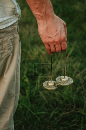 Photo for Indian tingsha bells for meditation and yoga in the hands of a man, sound vibrations for healing and relaxing 1 - Royalty Free Image