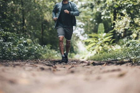 Foto de Estilo de vida saludable joven fitness hombre corriendo el bosque. Entrenamiento al aire libre, Concepto de estilo de vida saludable. - Imagen libre de derechos