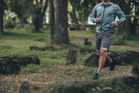 Foto de Estilo de vida saludable joven fitness hombre corriendo el bosque. Entrenamiento al aire libre, Concepto de estilo de vida saludable. - Imagen libre de derechos