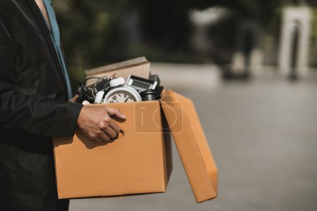 Téléchargez les photos : Un homme d'affaires viré ou démissionné de l'entreprise transporte des boîtes dans la rue à la recherche d'un nouvel emploi. Chômeurs, embauche, abandon du concept d'emploi - en image libre de droit
