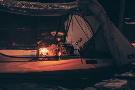 Téléchargez les photos : Une lampe à gaz est sur le sol de la tente la nuit et un sac avec un ukulélé et des chaussures à côté. Matériel de camping, vocation et concept de voyage. - en image libre de droit