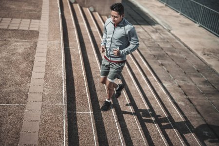 Ein Mann läuft im Stadtpark Treppen hinauf, um Cardio-Workout zu machen. Gesundheit und Lifestyle in der Großstadt.