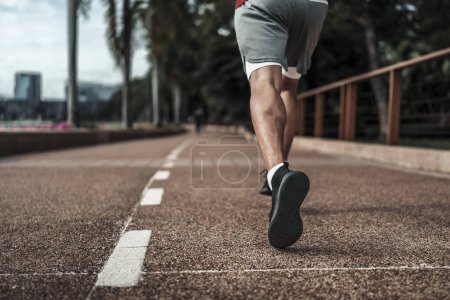 Foto de Un hombre corriendo en el parque del centro de la ciudad antes del entrenamiento cardiovascular, corriendo. Salud y estilo de vida en la gran ciudad concepto de vida. - Imagen libre de derechos