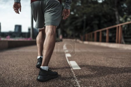 Foto de Un hombre se prepara para empezar a correr en el parque del centro de la ciudad antes del entrenamiento cardiovascular. Salud y estilo de vida en la gran ciudad concepto de vida. - Imagen libre de derechos