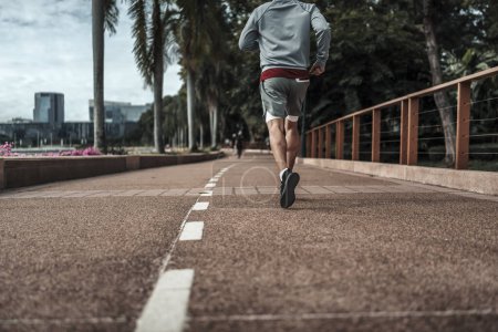 Foto de Un hombre corriendo en el parque del centro de la ciudad antes del entrenamiento cardiovascular, corriendo. Salud y estilo de vida en la gran ciudad concepto de vida. - Imagen libre de derechos