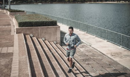 Foto de Un hombre corriendo por las escaleras en el parque del centro de la ciudad para hacer ejercicio cardiovascular. Salud y estilo de vida en la gran ciudad concepto de vida. - Imagen libre de derechos