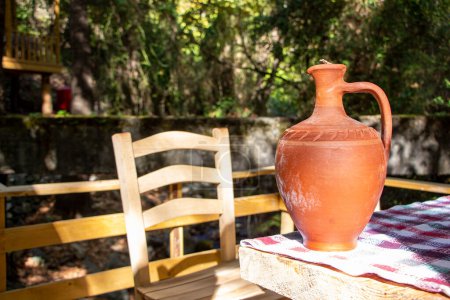 Foto de La jarra de barro sobre una mesa de madera en el jardín. Jarra de barro tradicional hecha a mano. Estilo vintage. - Imagen libre de derechos