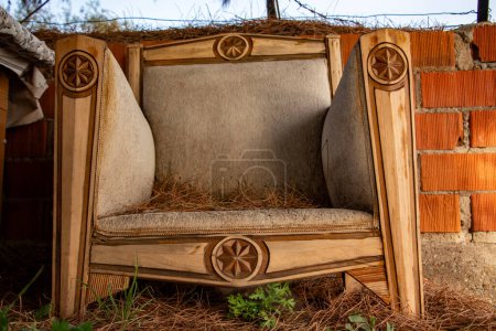 Foto de Muebles de madera hechos de materiales naturales en el jardín. Sillón viejo abandonado en la playa cerca de la pared de ladrillo.Muebles vintage en la playa. - Imagen libre de derechos