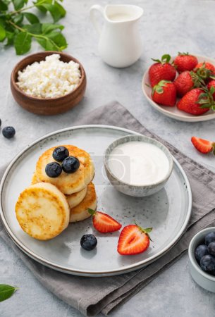 Photo for Cottage cheese pancakes with mint, blueberries, strawberries and milk on a gray  background. Healthy and delicious breakfast. - Royalty Free Image
