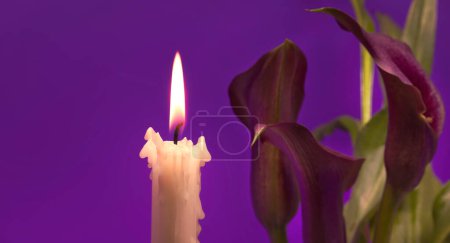 Foto de Llama de la vela y sépalos púrpura del lirio de Calla (Zantedeschia) iluminado por la luz de las velas sobre fondo violeta con espacio libre de copia - Imagen libre de derechos