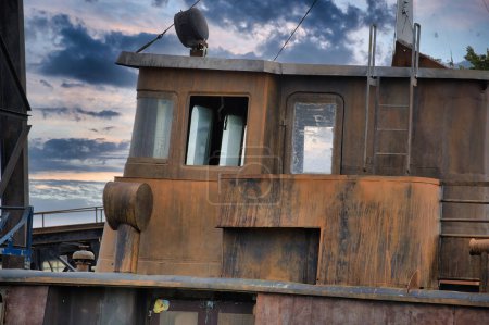 Photo for Enchanting view of an old, rusty boat, stationary and silent, against the backdrop of a cloudy sky, rusted surface and the weathered wood - Royalty Free Image