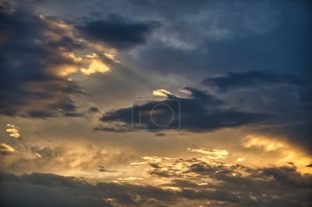 Photo for Breathtaking view of a cloudy sky, sun's rays make a gallant attempt to penetrate the thick layer of clouds, afterglow paints the sky creating a sense of tranquility and peace - Royalty Free Image
