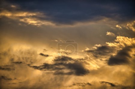 Photo for Sky with clouds which carry a dominant golden hue indicative a sunrise or sunset cumulus formation suggests a dynamic and dramatic sky with the sun either rising or setting in the backdrop - Royalty Free Image