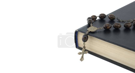 Foto de Rosario con cuentas de madera y un crucifijo colocado encima de una Biblia negra aislada sobre fondo blanco con espacio libre para copiar - Imagen libre de derechos
