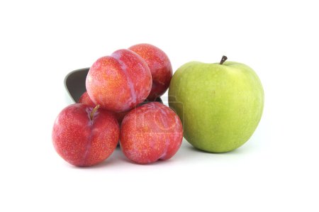 Foto de Colección de frutas frescas compuestas por ciruelas rojas y manzana verde brillante dispuestas sobre un fondo blanco - Imagen libre de derechos