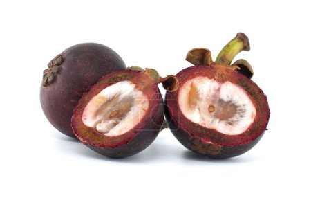 Ganze und halbierte Mangofrüchte zeigen ihr weißes Fruchtfleisch, gesprenkelt mit dunkelvioletten Flecken und mit zwei erkennbaren schwarzen Samen, die vor weißem Hintergrund stehen.