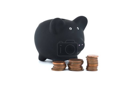 Black piggy bank accompanied by three distinct stacks of coins, ordered by size from largest to smallest and arranged from left to right isolated on white background