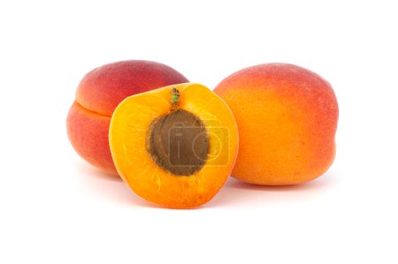 Group of fresh whole apricots and one cut in half to reveal its interior, isolated on a white background