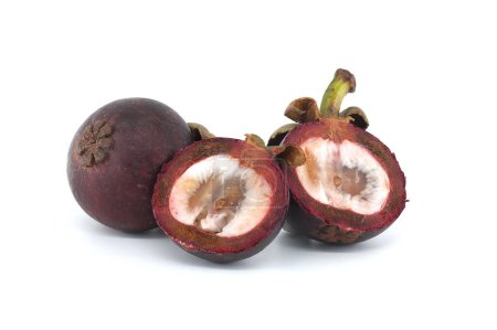 Whole and cut in half mangosteen fruits revealing its white interior flesh dotted with dark purple spots and containing two visible black seeds isolated on white background