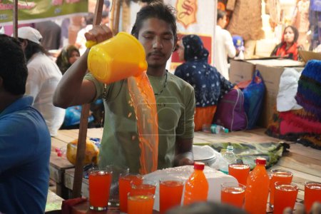 Téléchargez les photos : 7 avril 2023, Zakaria Street, Kolkata, Bengale occidental, Inde. Jeune garçon âgé vendant des boissons rafraîchissantes à la rue Zakaria pendant le mois de Ramjan - en image libre de droit