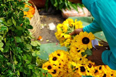 Käufer kaufen Sonnenblume von einem Blumenverkäufer auf dem Howrah-Blumenmarkt