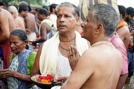 Téléchargez les photos : Prêtre hindou aide à effectuer Tarpan pendant Mahalaya à Babu Ghat - en image libre de droit