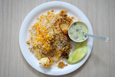 Tischplatte mit indischem Huhn Biryani Teller serviert mit Ei und Kartoffeln in weißem Teller