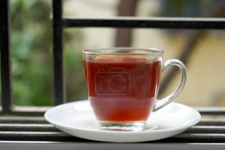 TRANSPARENT CUP WITH RED LIQUOR TEA BESIDE THE WINDOW
