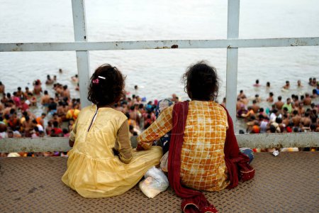 Foto de Dos niños desfavorecidos toman parte en Mahalaya Tarpan desde lejos en Kolkata Ganga Ghat - Imagen libre de derechos