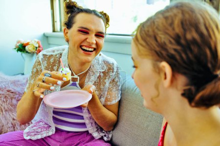 Photo for Cheerful young adult with birthday cupcake smiling and laughing with friend - Royalty Free Image