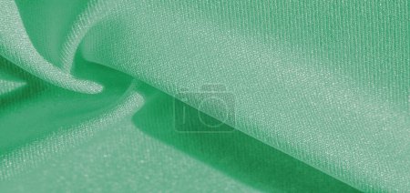 green silk. Smooth elegant green luxury silk fabric can be used as abstract background with copy space, close up. colorful texture