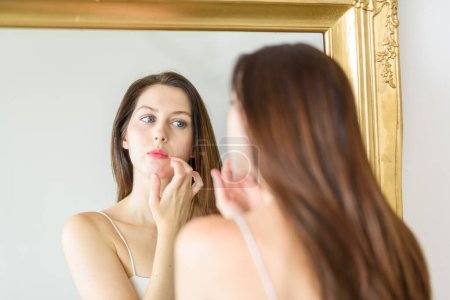 Photo for Tightly framed shot of girl touching up her makeup in a large, ornate mirror - Royalty Free Image