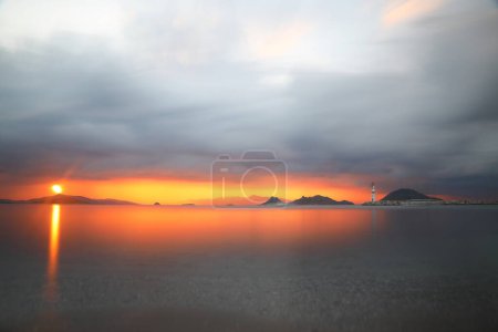 Photo for Seascape at sunshine. Lighthouse and sailings on the coast. Seaside town of Turgutreis and spectacular sunshine. Long Exposure shoot. tranquility scene. - Royalty Free Image