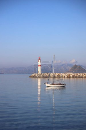 Paisaje marino al sol. Faro y veleros en la costa. Ciudad costera de Turgutreis y espectacular sol