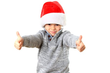 Photo for Cute five year old boy wearing a Santa Hat for Christmas with two thumbs up. - Royalty Free Image